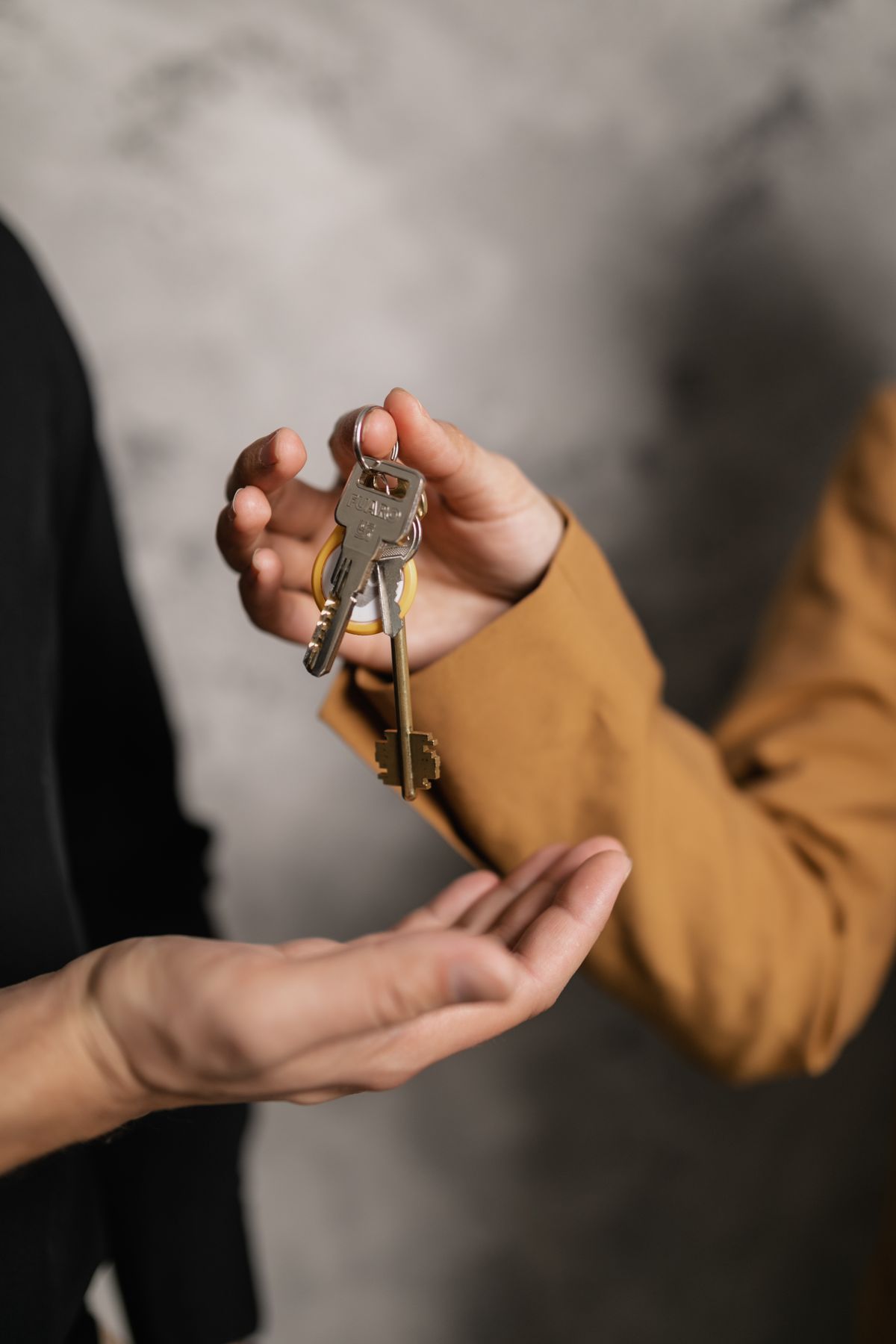 Hands exchanging a set of property keys, representing TAKL's onsite building management