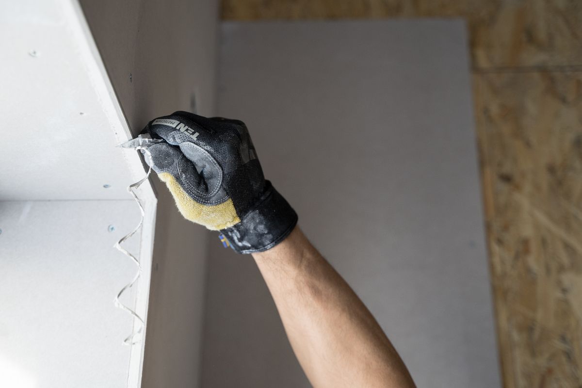 Close-up of a hand in a work glove finishing a drywall repair